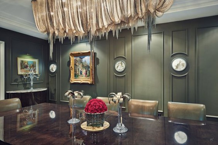 photograph of a dining room with olive green walls and a dripping chain chandelier, visual storytelling by marco joe fazio