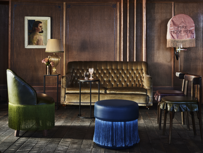 Sitting area with a gold tufted sofa, a green fringed chair and blue fringed ottoman at the Imperial Hotel Erskineville Sydney Australia - a LGBTQIA+ hotel