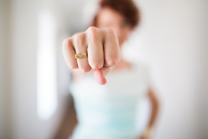 photo of a woman with her hand in a fist wearing a ring that says i am badass - how to be a powerful woman