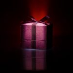 red gift box with red bow on dark toned background - luxurious gifts for every occasion