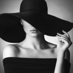 fashion forward luxury brands - Studio shot of young beautiful woman wearing hat on dark background