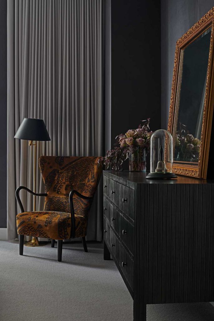 interior design detail of wing chair and dresser gold and black modern victorian