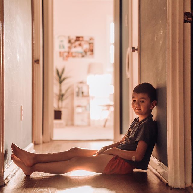 young boy sitting in hallway Photo by Barbara Larson