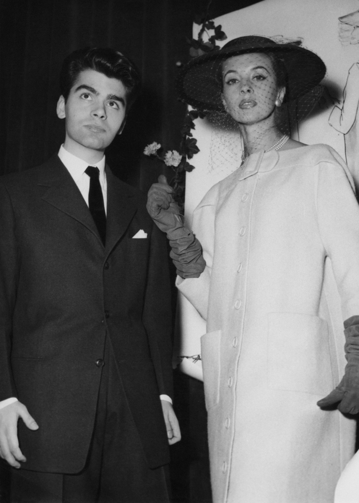 womens wear designers - Karl Lagerfeld after winning the coats category in a design competition sponsored by the International Wool Secretariat, Paris, 14th December 1954. With him is a model wearing his design. The competition win led to Lagerfeld being hired as assistant to Pierre Balmain. (Photo by Keystone/Hulton Archive/Getty Images)
