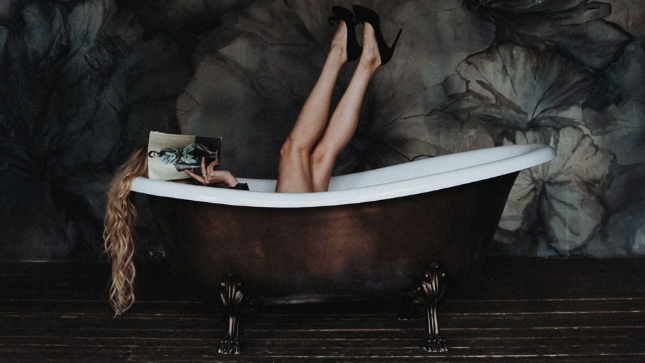 female hormone cycle self-care practices - woman with heels on and legs up in tub - photo by klara kulikova unsplash