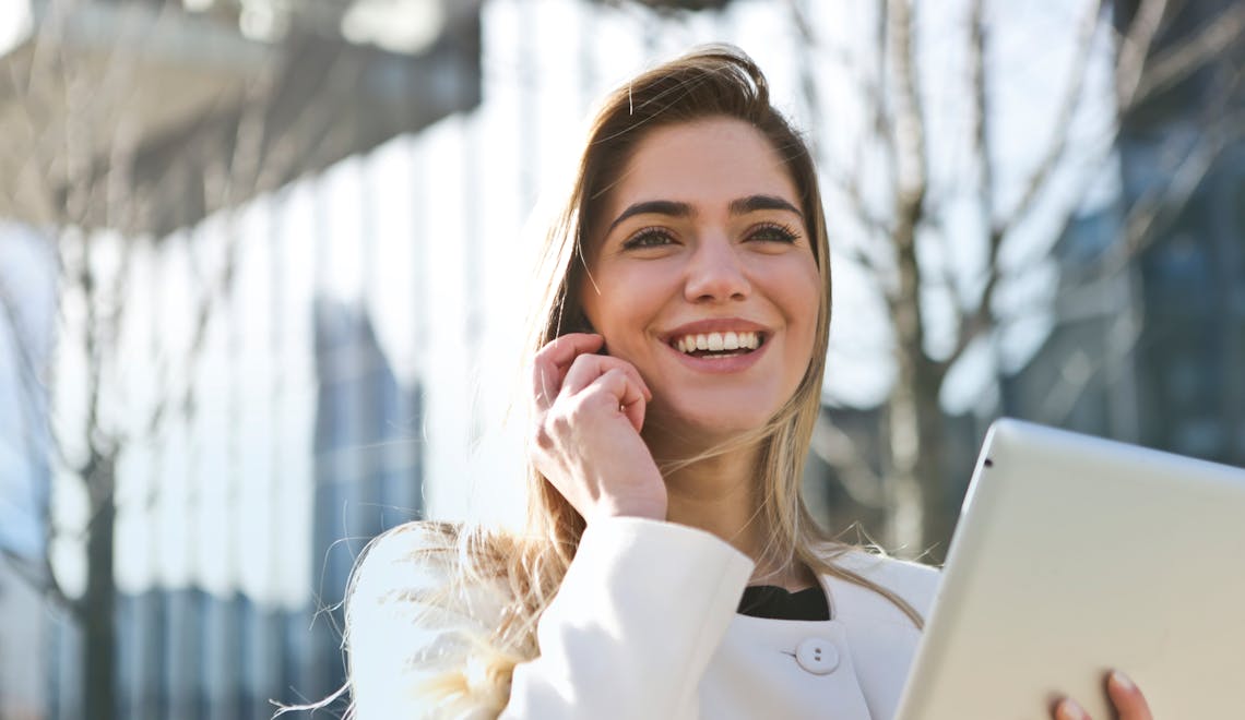 Woman in white blazer holding a tablet