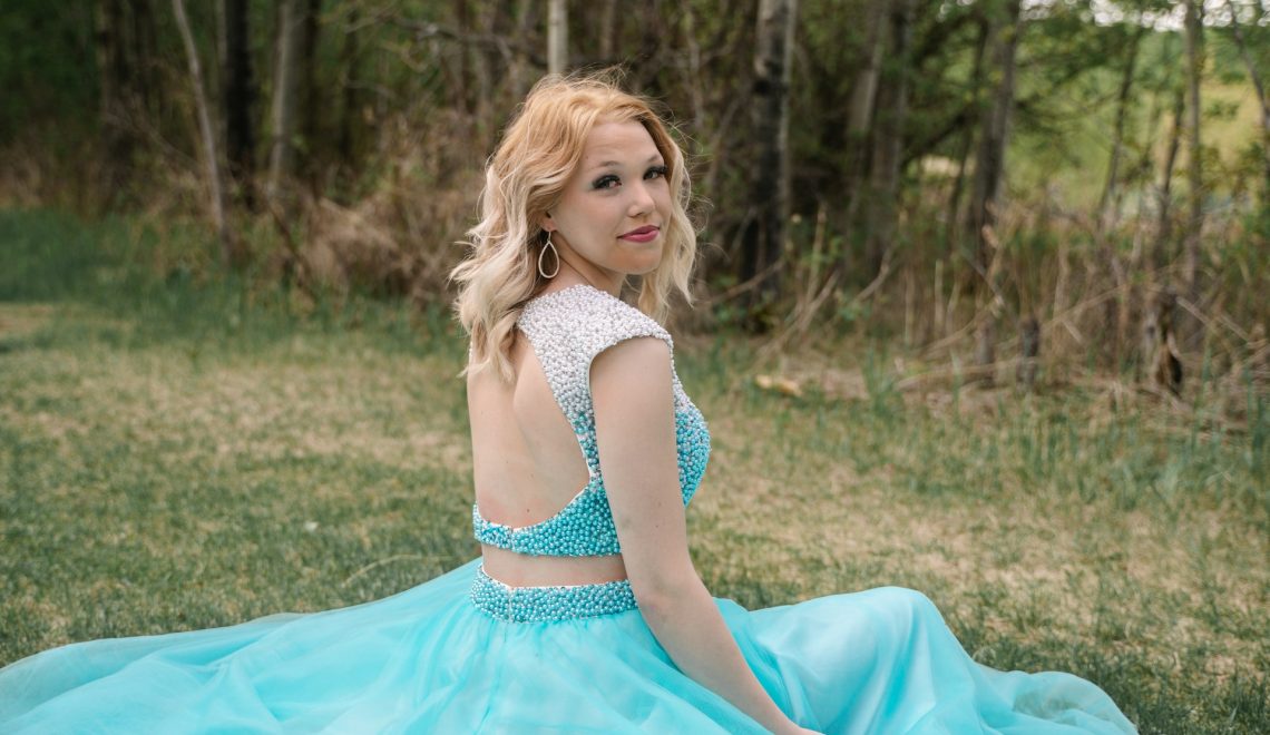 Woman in a blue dress sitting in a grassy area