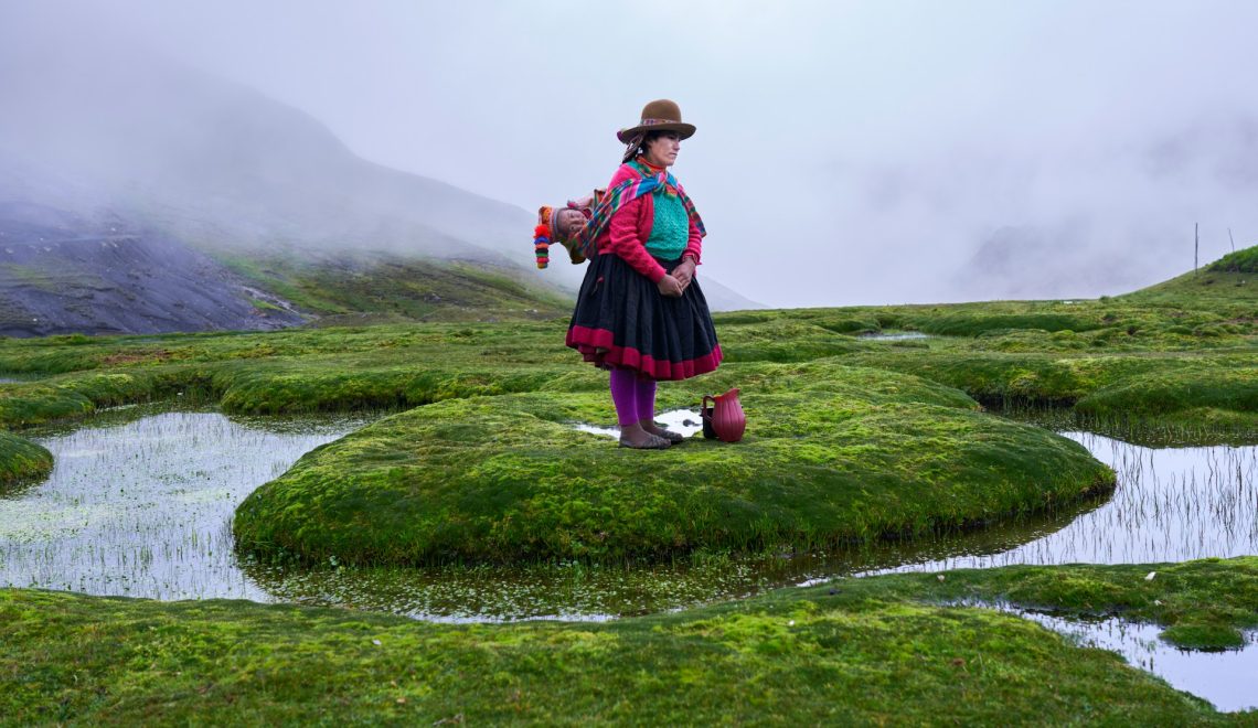 quechua peruvian woman with her baby walking through the mountains on a foggy day