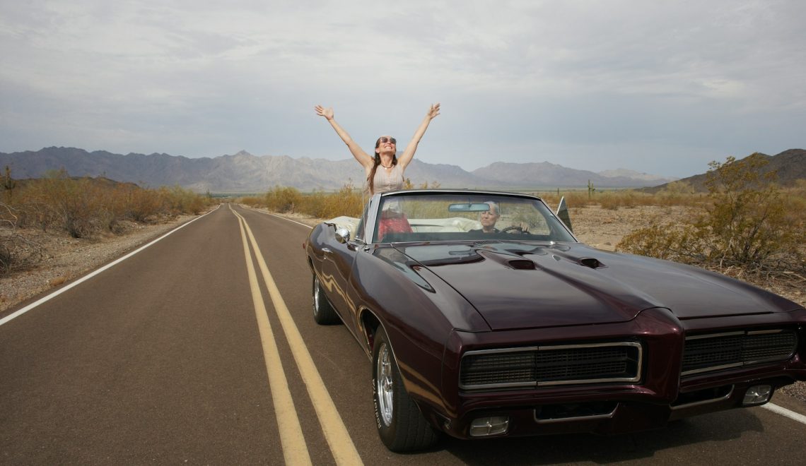 A woman standing on a car in the middle of the road