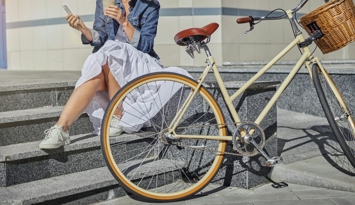 vintage bicycle in front of a woman wearing a dress with sneakers