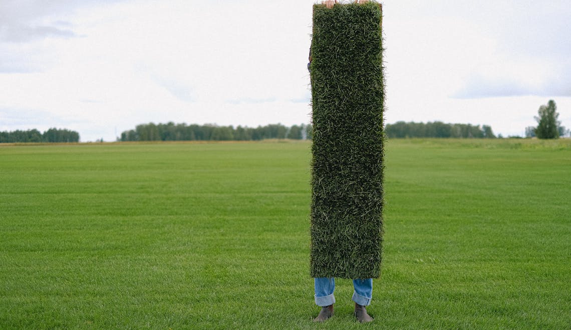 person holding a piece of artificial grass turf