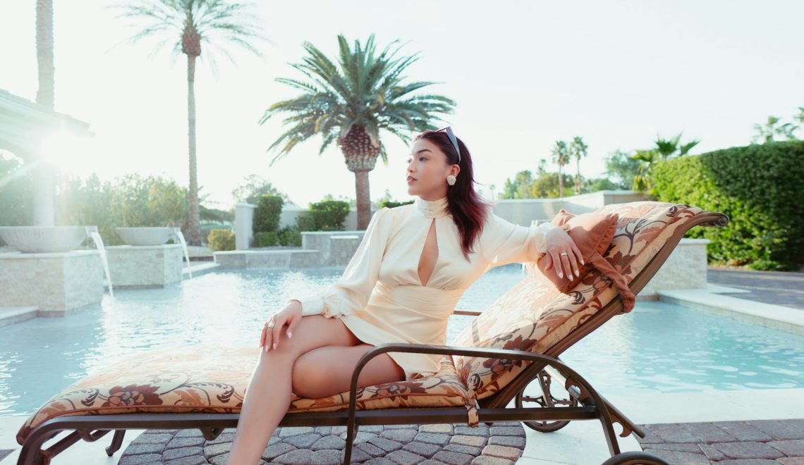 a woman sitting on a bench next to a pool