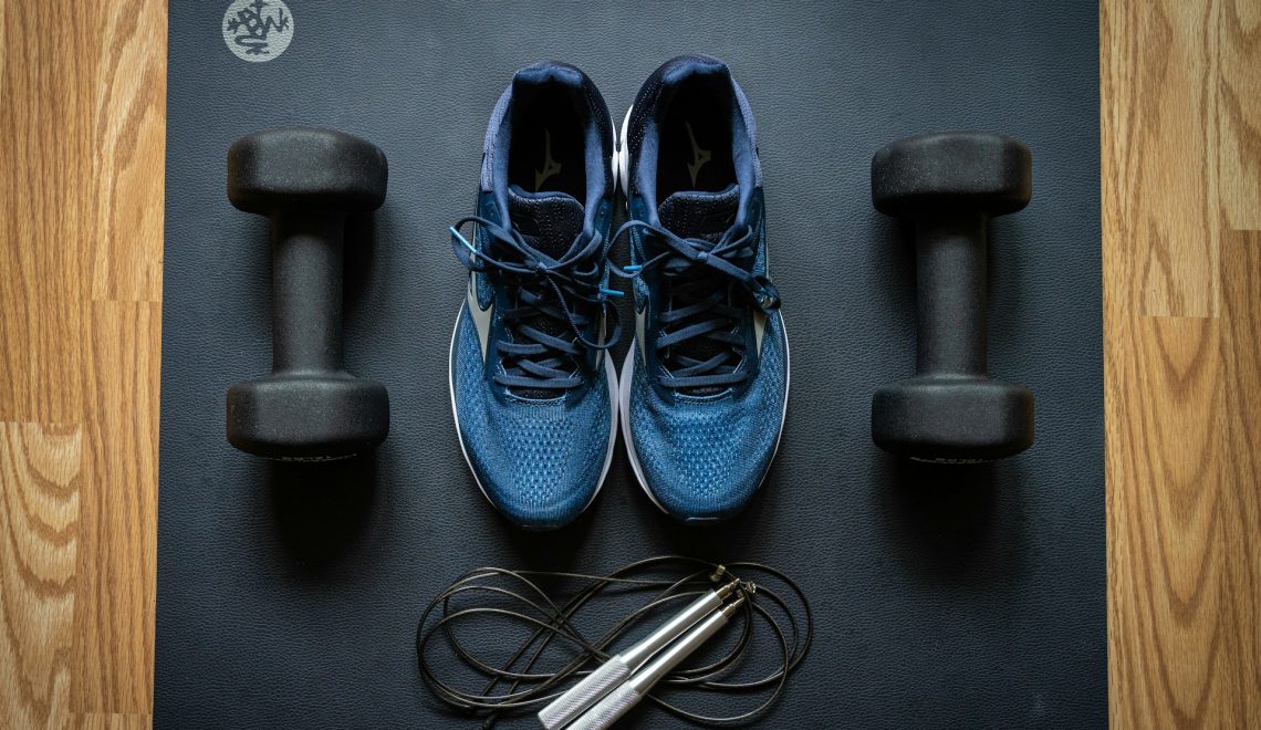 Black dumbbells and blue shoes on top of a black mat
