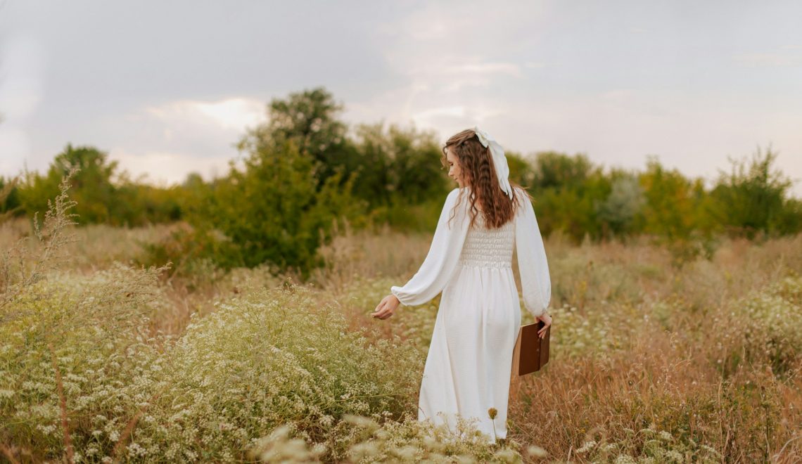 A woman in a white dress walking through a field