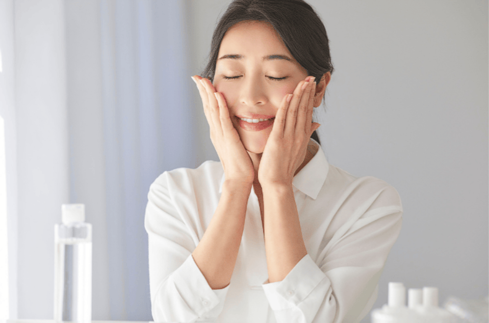 woman smiling and touching her face