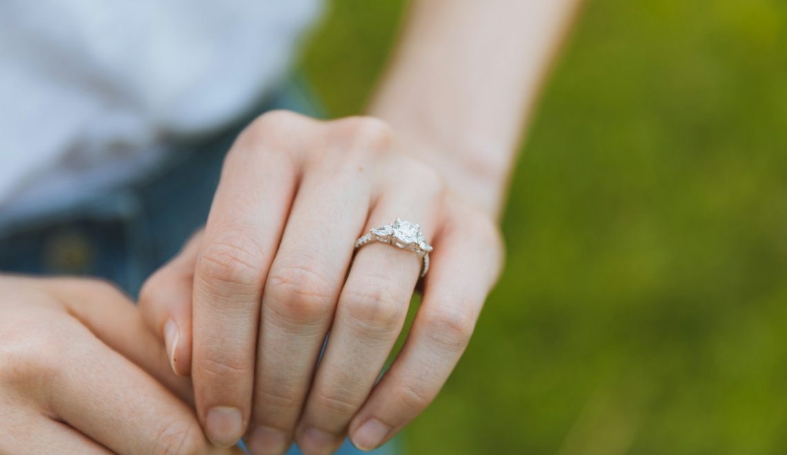 a close up of a woman's hand with an engagement ring