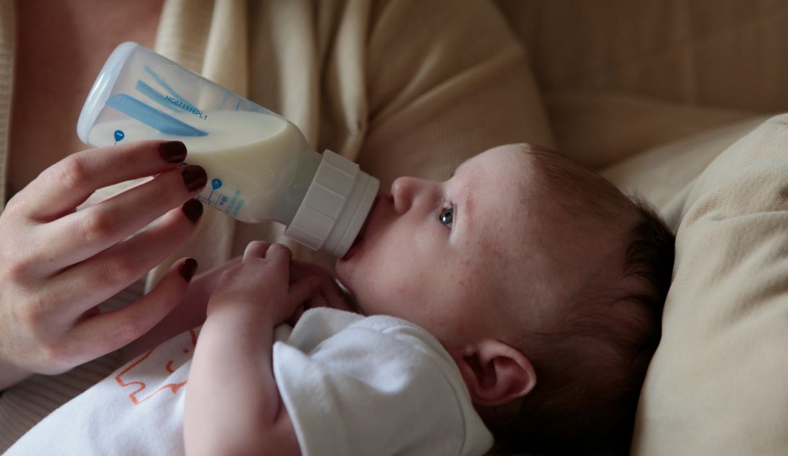 a woman feeding a baby with a bottle of milk