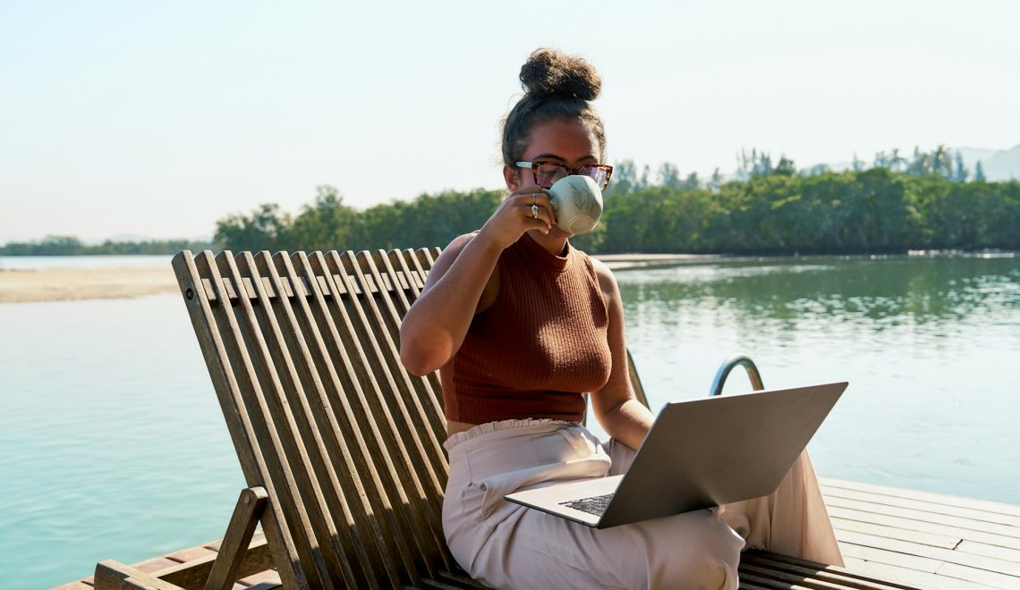 donna seduta su una sedia fuori con un computer portatile in grembo