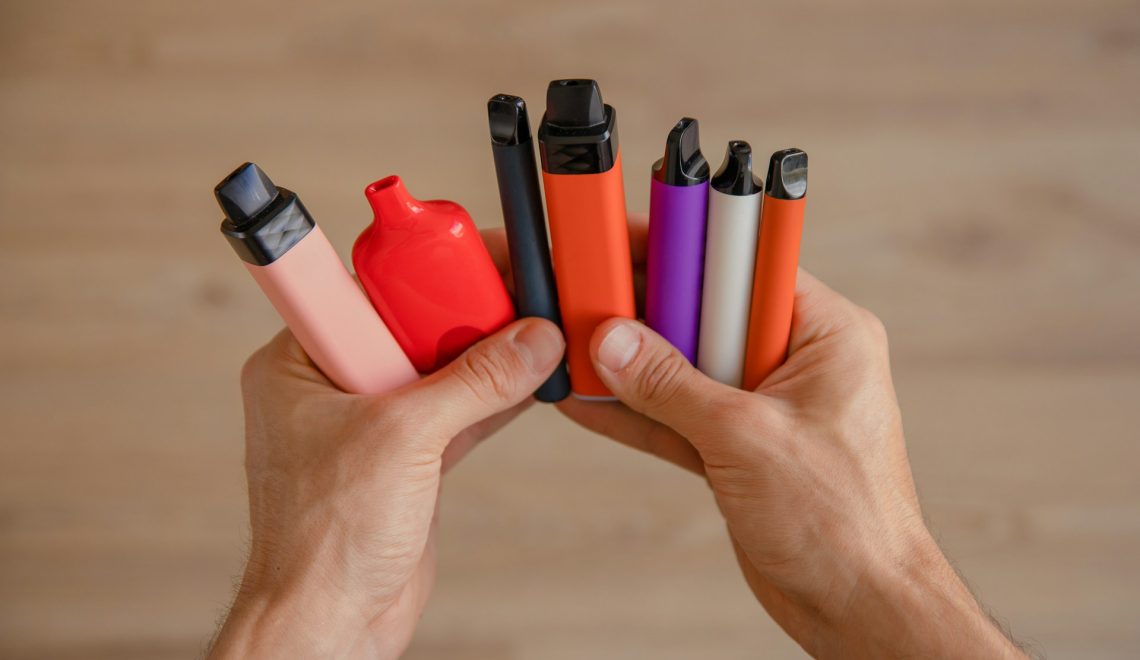 man holding different vapes
