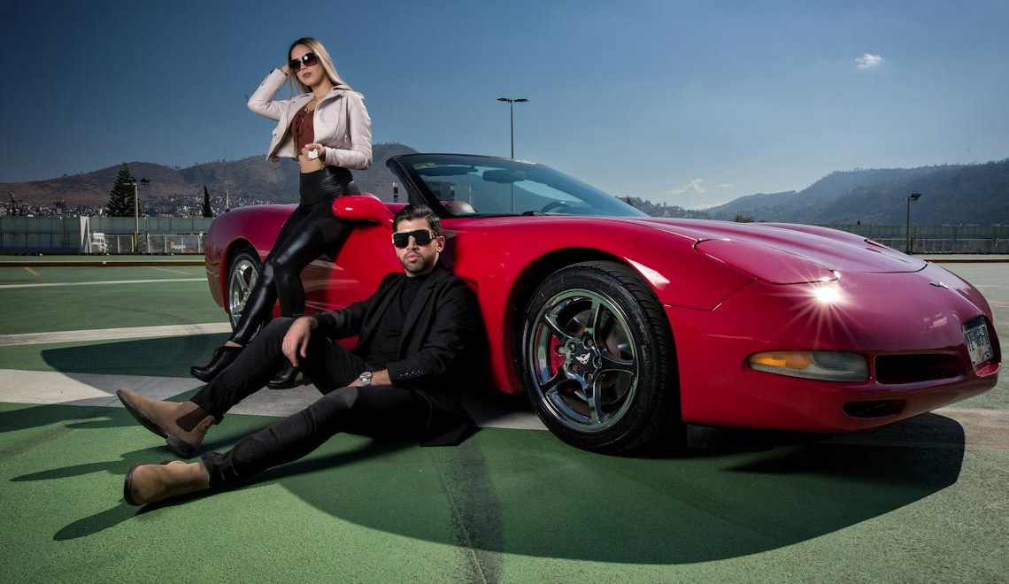 two people posing by a car