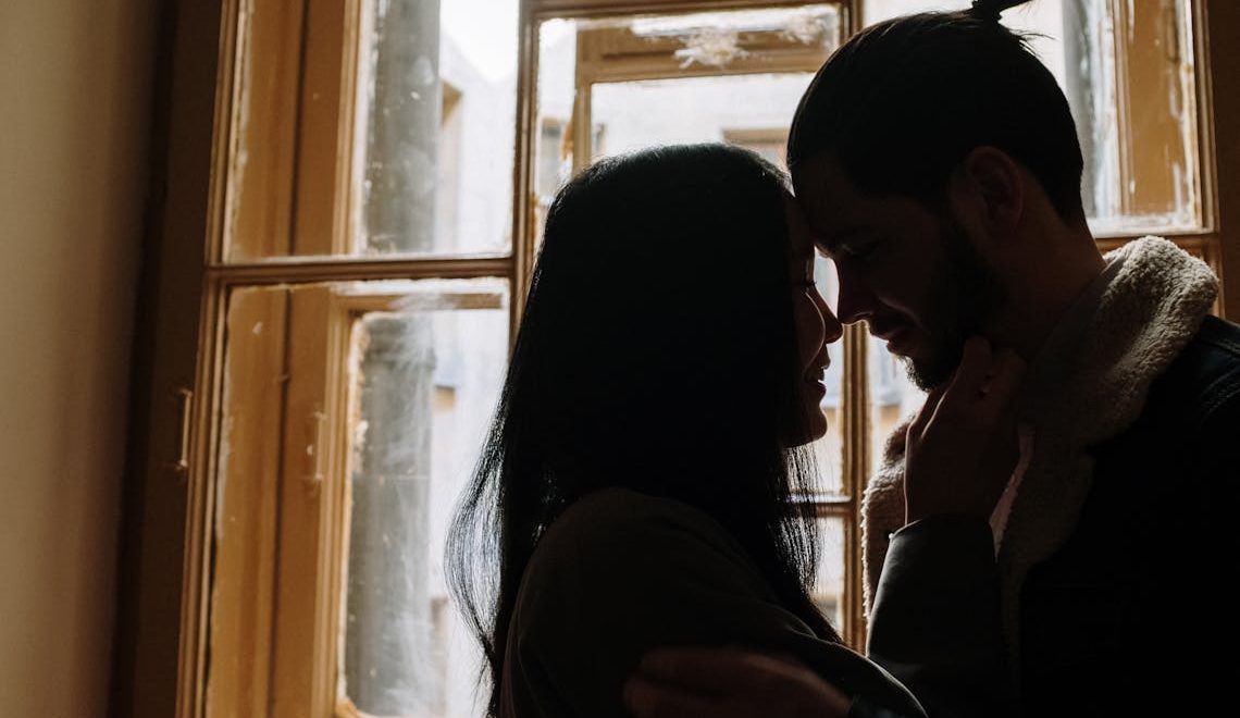 A man and a woman in front of a window