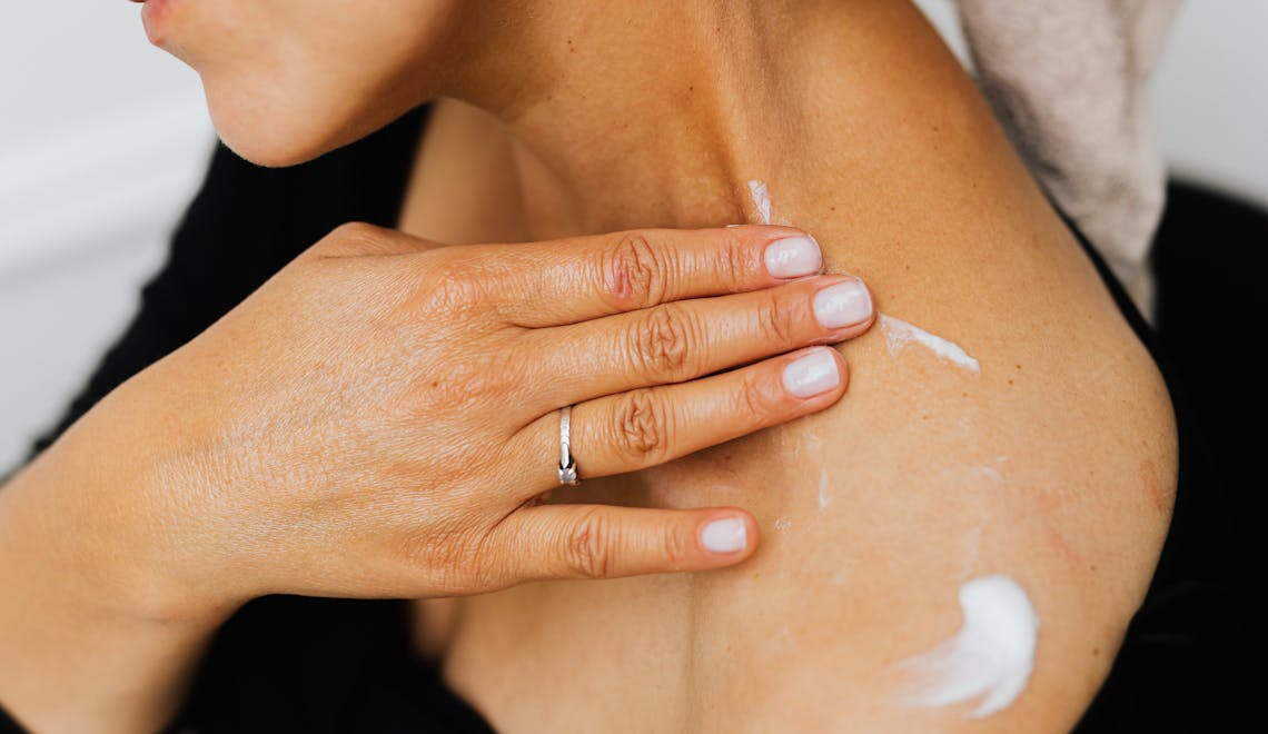 A woman applying cream on her skin