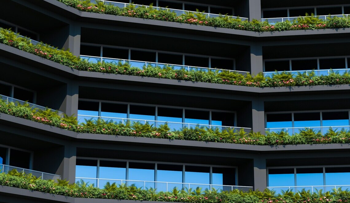 Modern eco-friendly apartment building facade featuring balconies lined with green plants and vertical gardens.