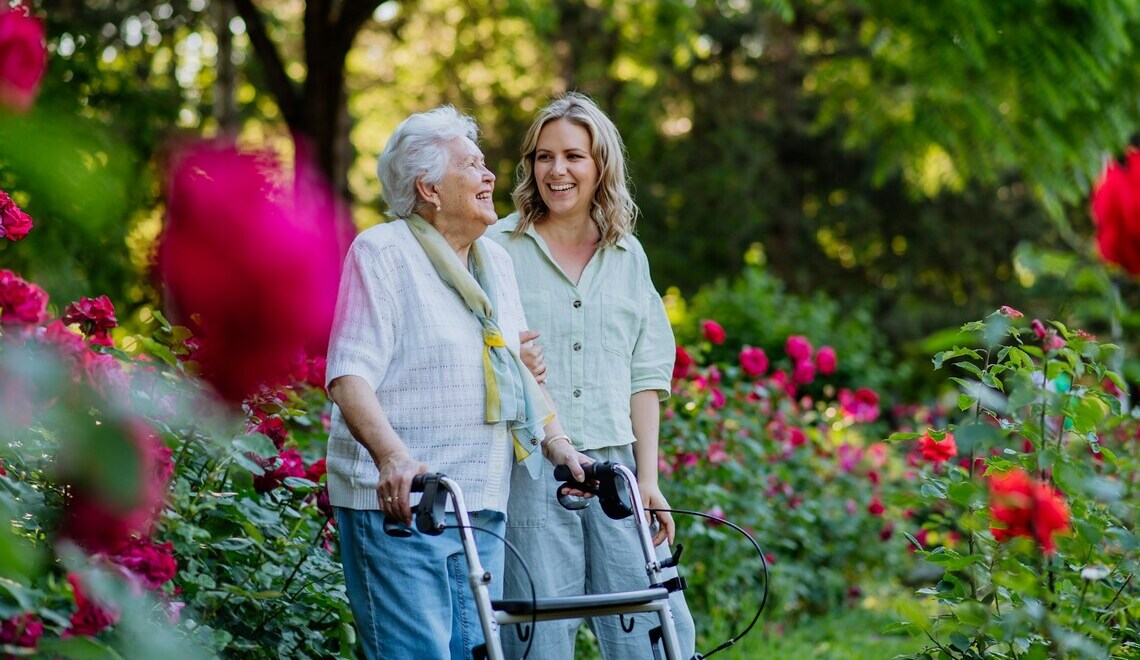 A woman walking with an elderly woman through a blooming garden