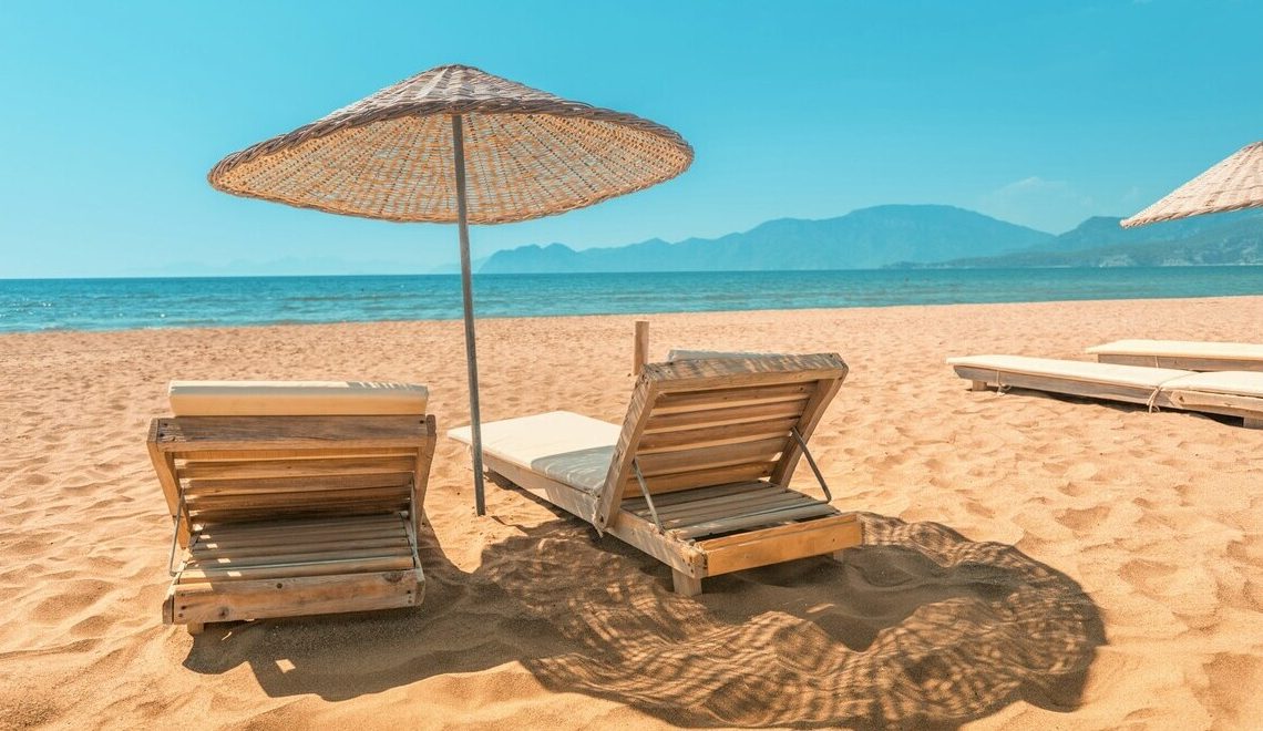 Wooden sun loungers with a parasol on a sandy beach