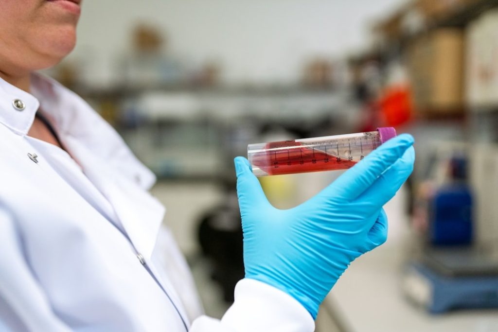 A technician in a white coat examining vials in a laboratory