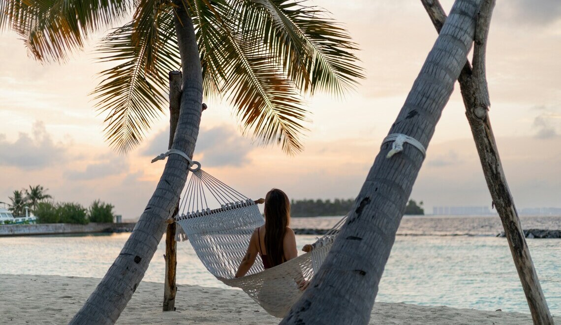A woman sitting on a hammock on the beach