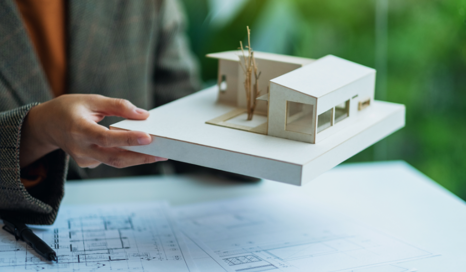 Person holding an architectural scale model of a modern house