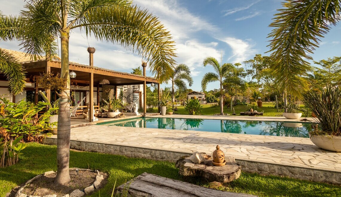 a pool surrounded by palm trees next to a house