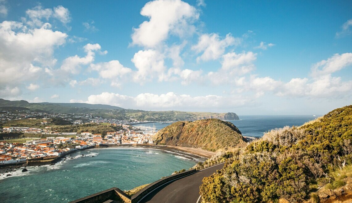 A cyclist riding a coastal road in Portugal with the ocean behind