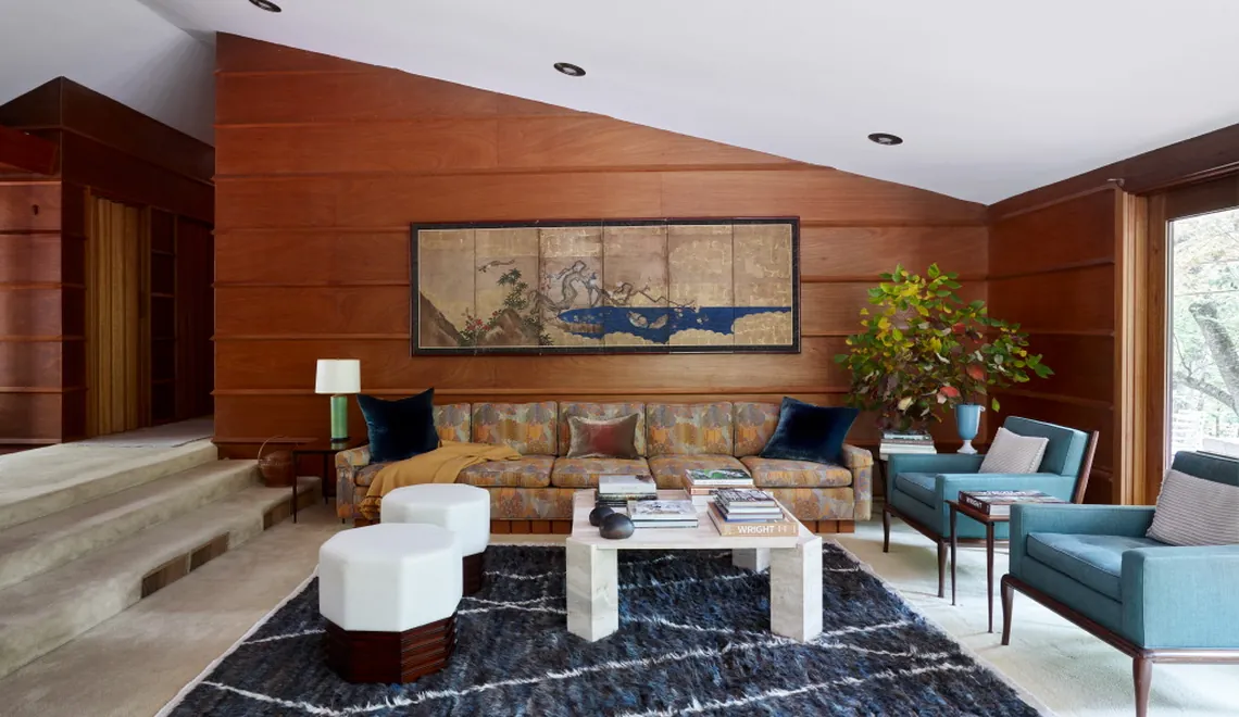 living room by studio magness with wood paneling and vintage rug