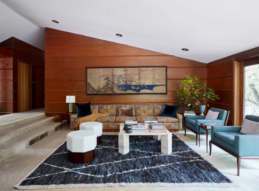 studio magness living room with warm wood paneling and blue armchairs