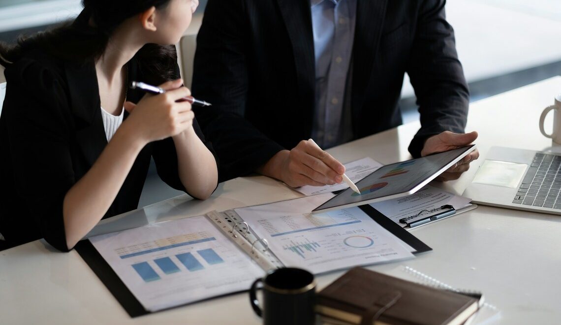 Two professionals in business attire reviewing charts