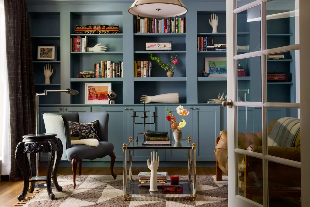 spooky interior design library with salvaged white porcelain glove mold hands on dusty blue bookshelves by steven miller